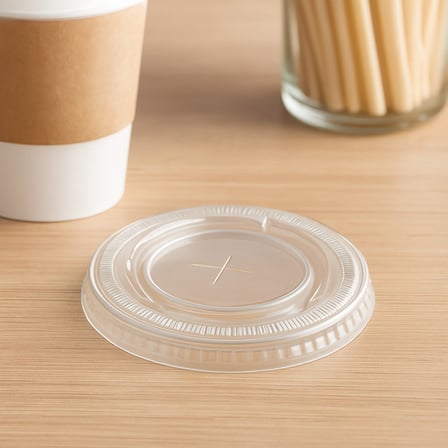 Clear 9 oz PET plastic cold cup flat lid placed on a table.jpg