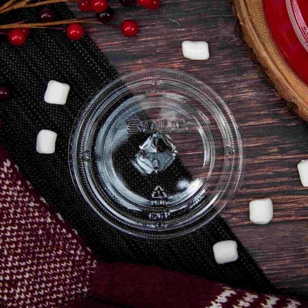 Solo Clear PET Plastic Flat Lid with Straw Slot, Fits 12 to 24 ounces on a Wooden Surface.jpg
